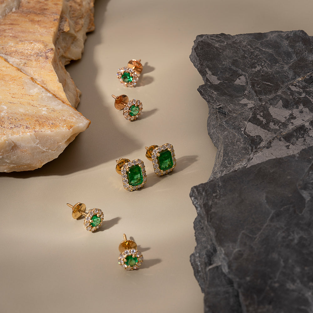 Zambian emerald and diamond halo stud earrings in 18K gold between light and dark stones