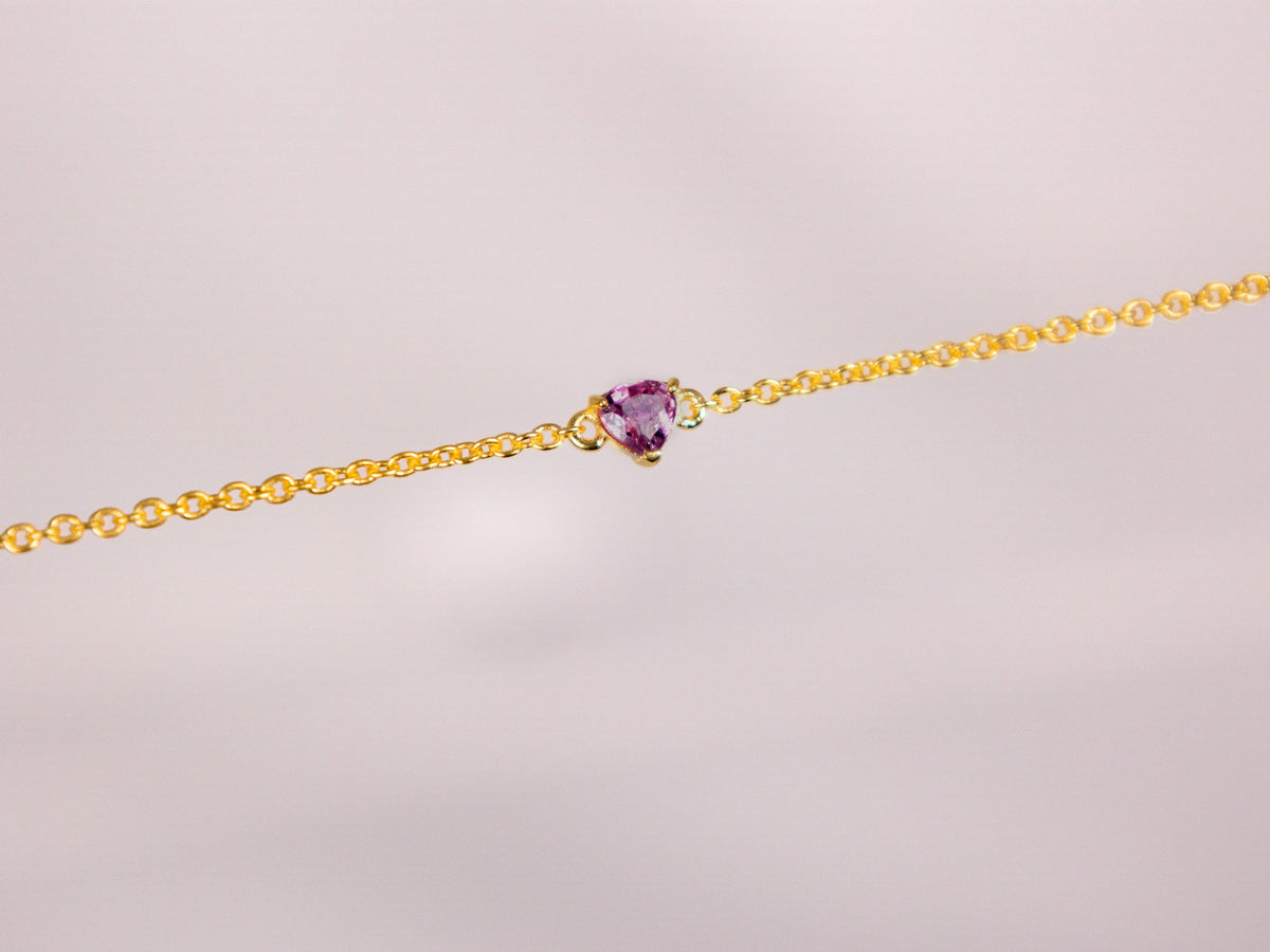 Close up of a natural pink sapphire heart on a yellow gold plated 925 silver chain