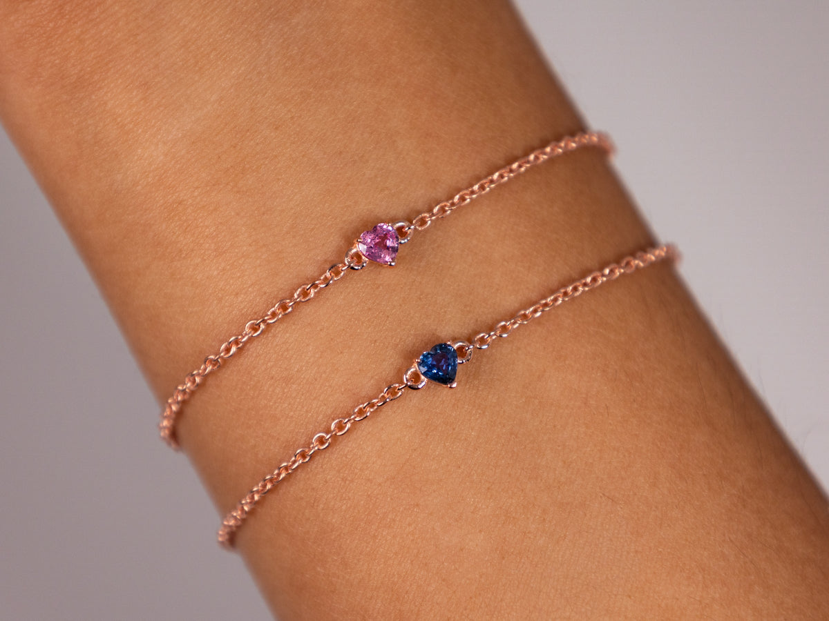Stack of pink and blue sapphire heart bracelets worn together, a birthstone push present idea