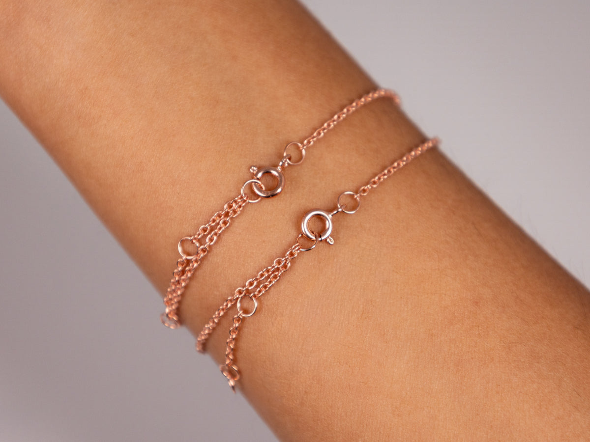Two rose gold plated 925 sterling silver sapphire heart bracelets on the wrist