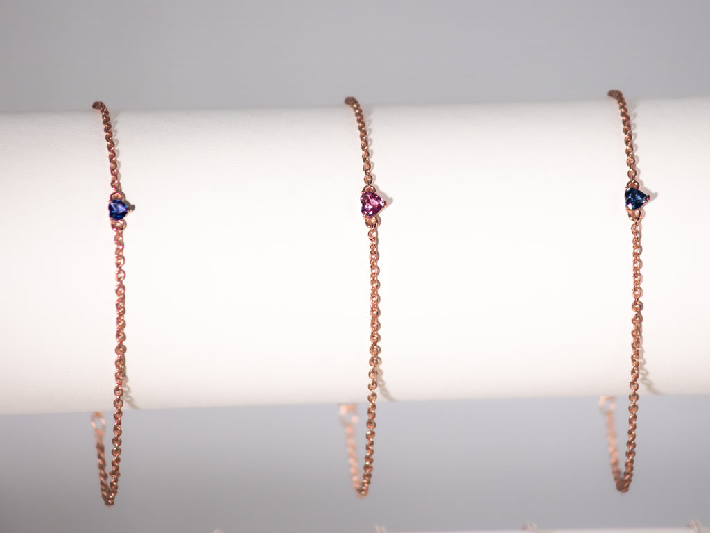 Pink and blue sapphire heart bracelets in rose gold plated 925 silver on a display