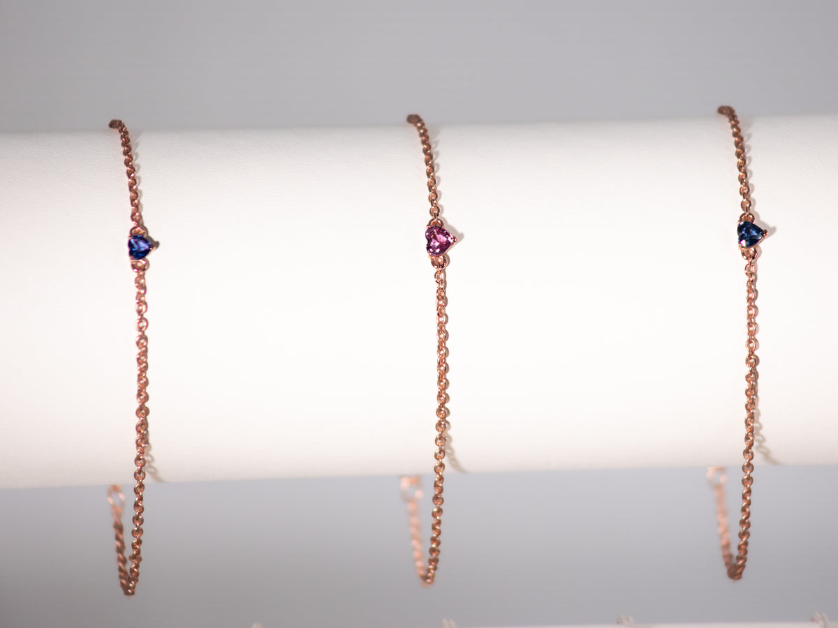 Pink and blue sapphire heart bracelets in rose gold plated 925 silver on a display