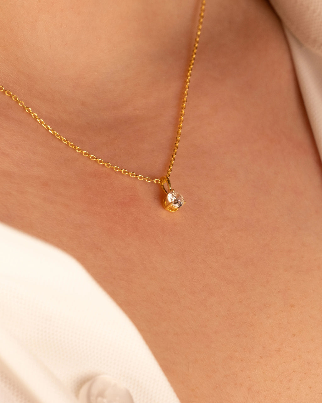 Yellow gold plated solitaire pendant worn at the collarbone