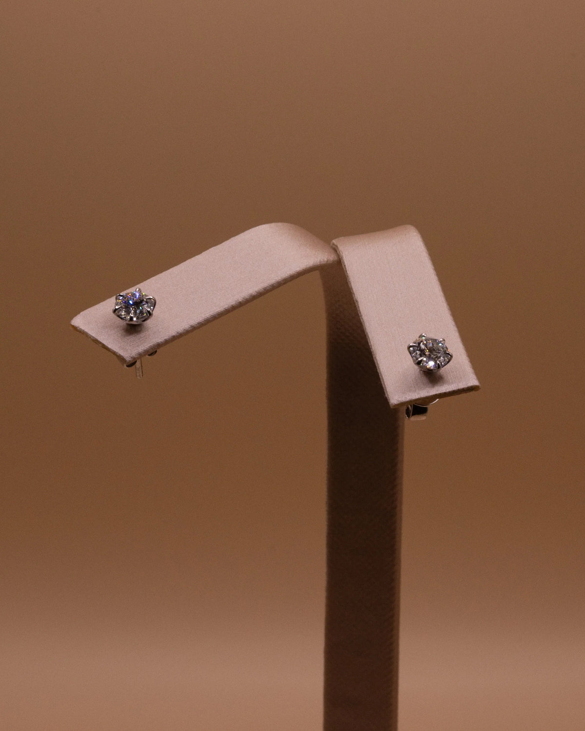Pair of white rhodium diamond studs, 1 ct total, on an earring stand