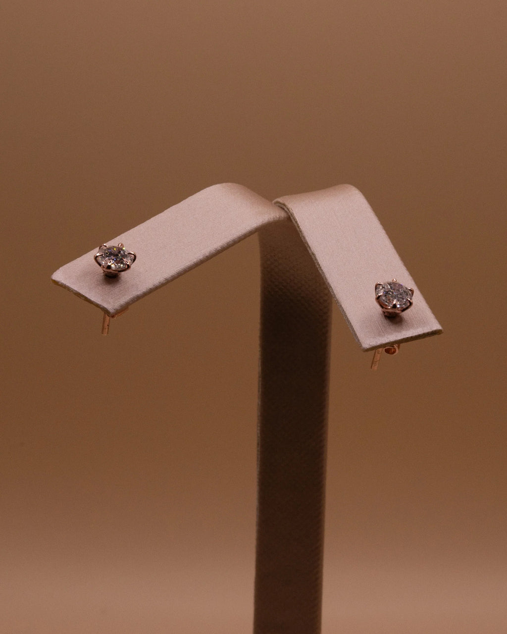 Pair of rose gold plated diamond studs on an earring stand