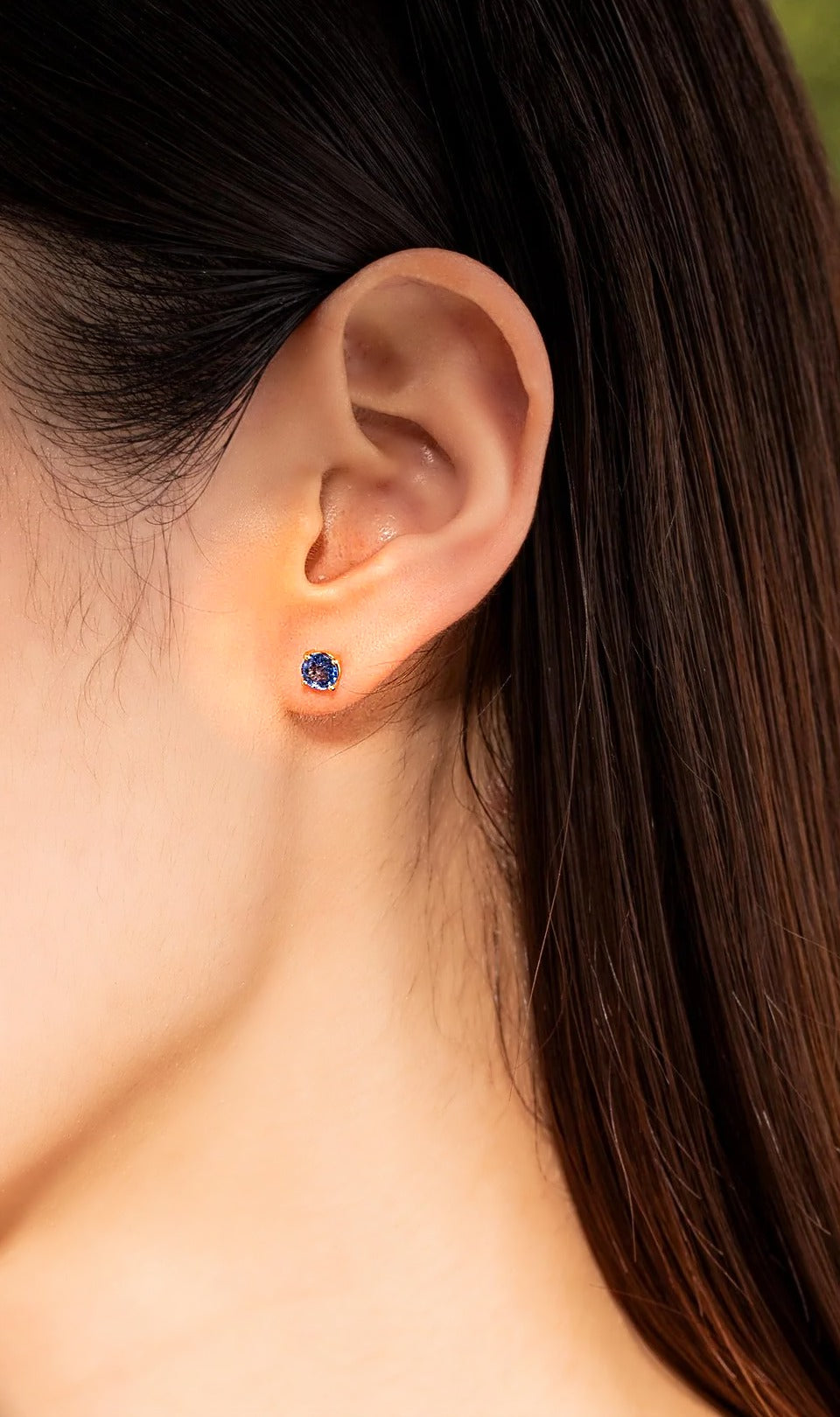 Blue sapphire screw back stud earring in 18K gold, worn on the ear