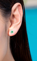Ohrstecker mit sambischem Smaragd und Diamant-Blüten-Halo in 18K Gelbgold, am Ohr getragen