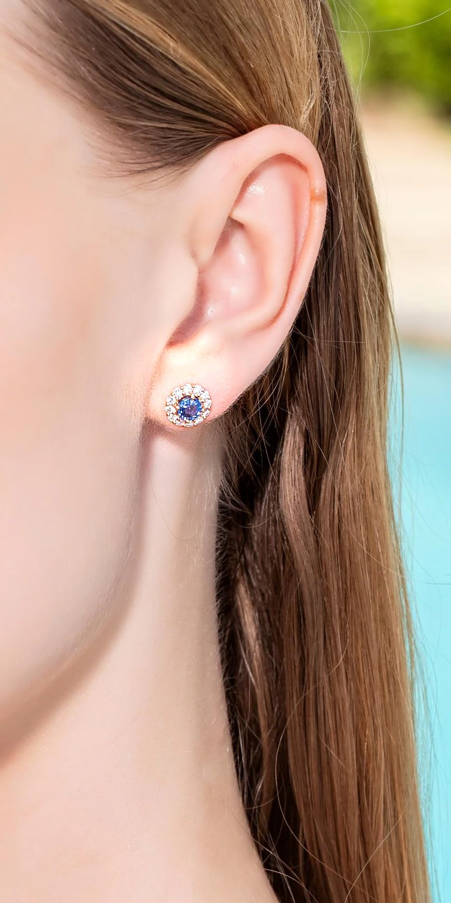 Blue sapphire and diamond halo stud earring in 18K yellow gold, worn on the ear