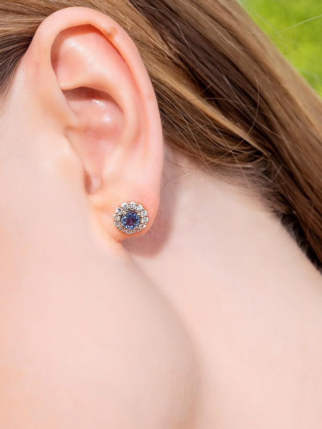 Blue sapphire and diamond halo stud earring in 18K yellow gold, worn on the ear