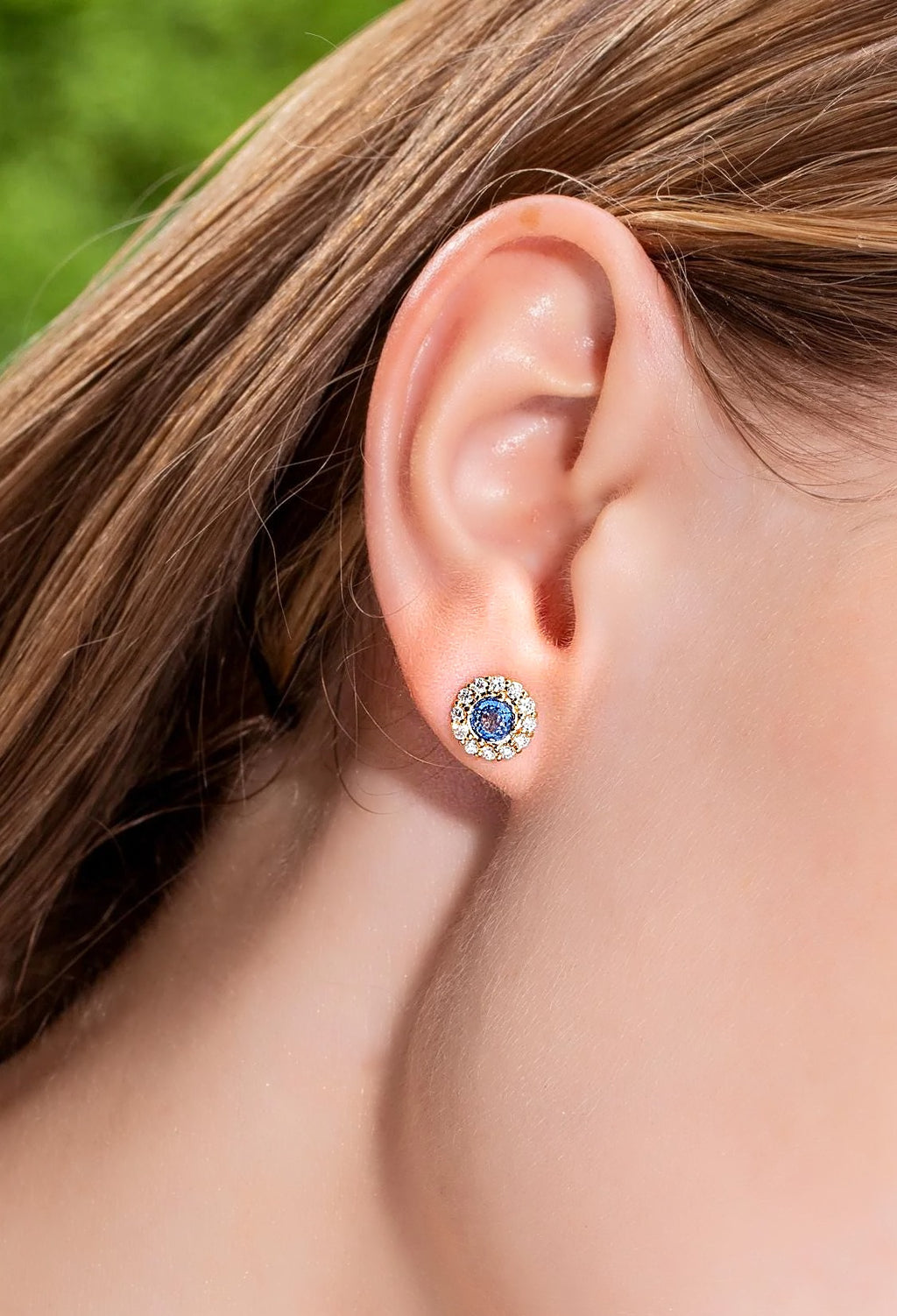 Blue sapphire and diamond halo stud earring in 18K yellow gold, worn on the ear