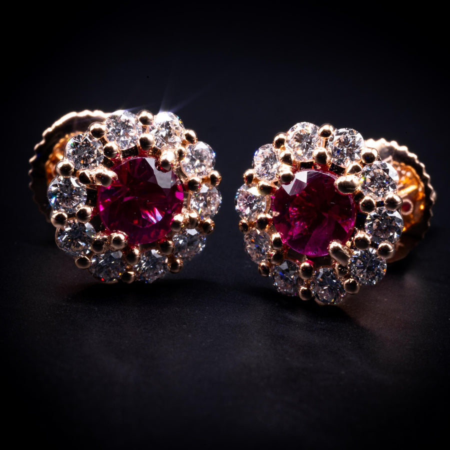 Ruby and diamond halo stud earrings in solid 18K rose gold on a dark background