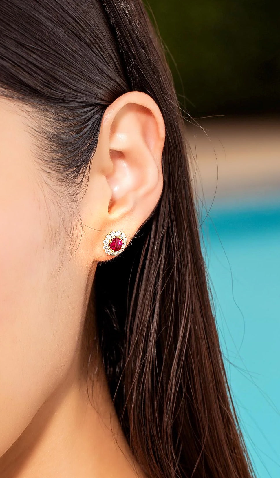Ruby and diamond halo stud earring in 18K gold, worn on the ear