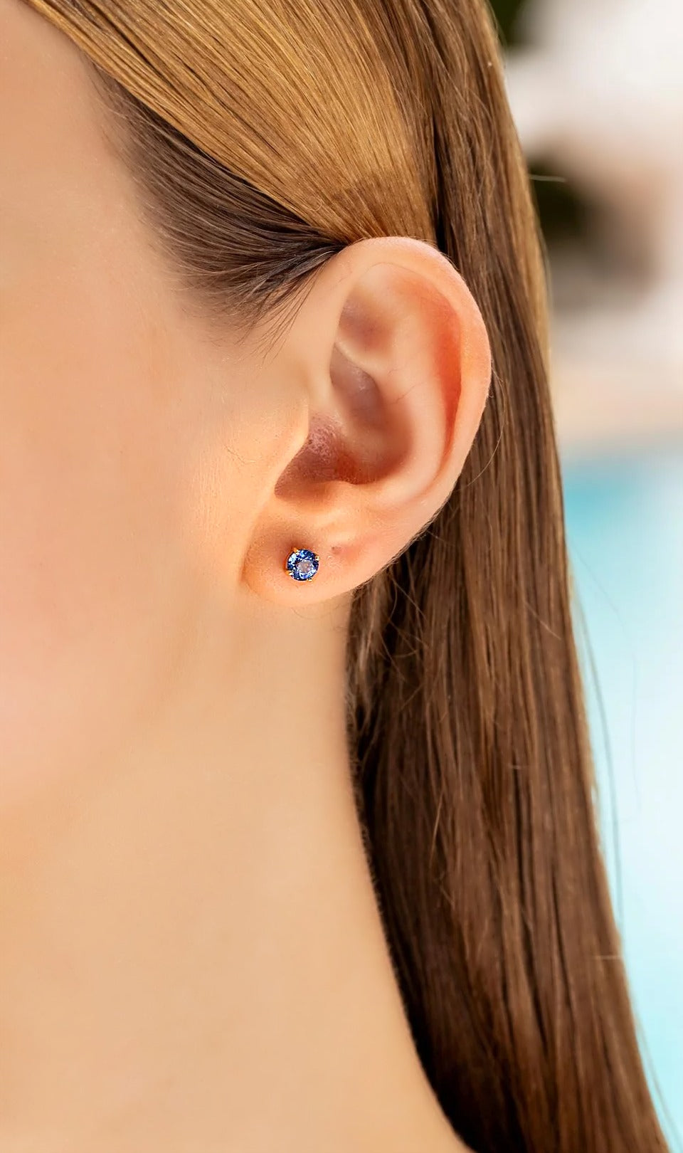 Blue sapphire screw back stud earring in 18K gold, worn on the ear