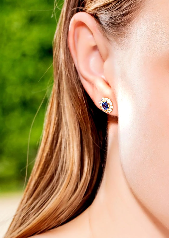 Blue sapphire and diamond halo stud earring worn on the ear with long hair behind the shoulder