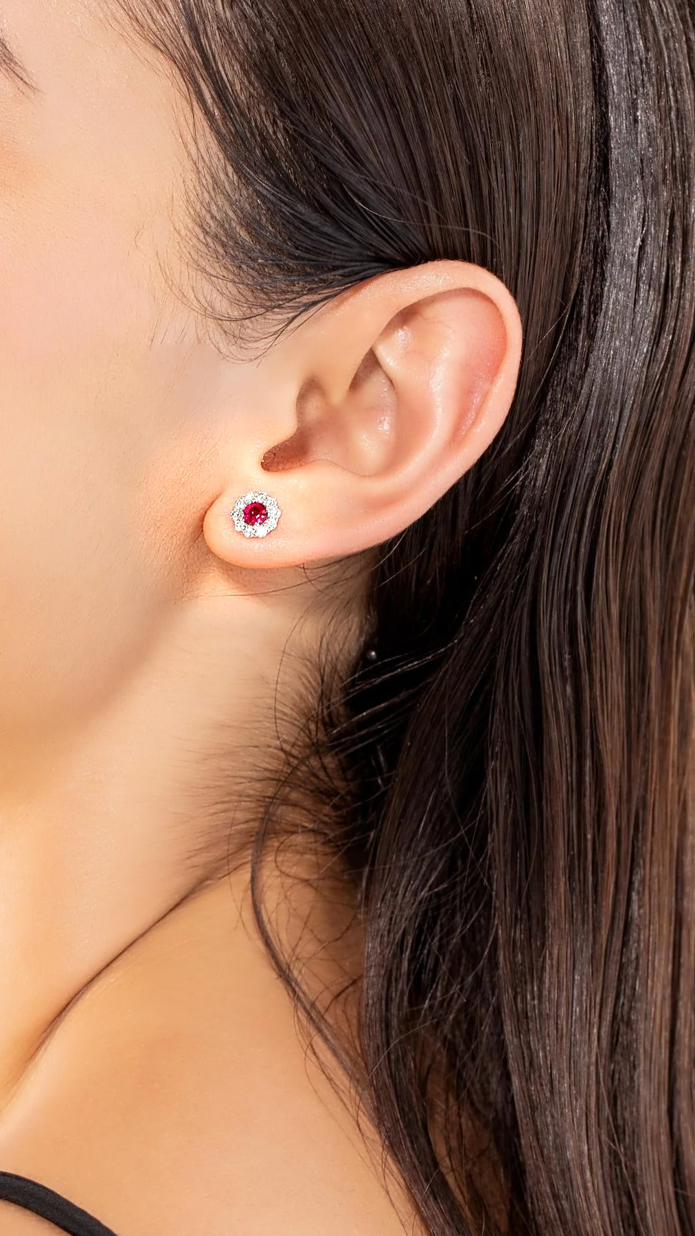 Ruby and diamond flower halo stud earring in 18K white gold, worn on the ear