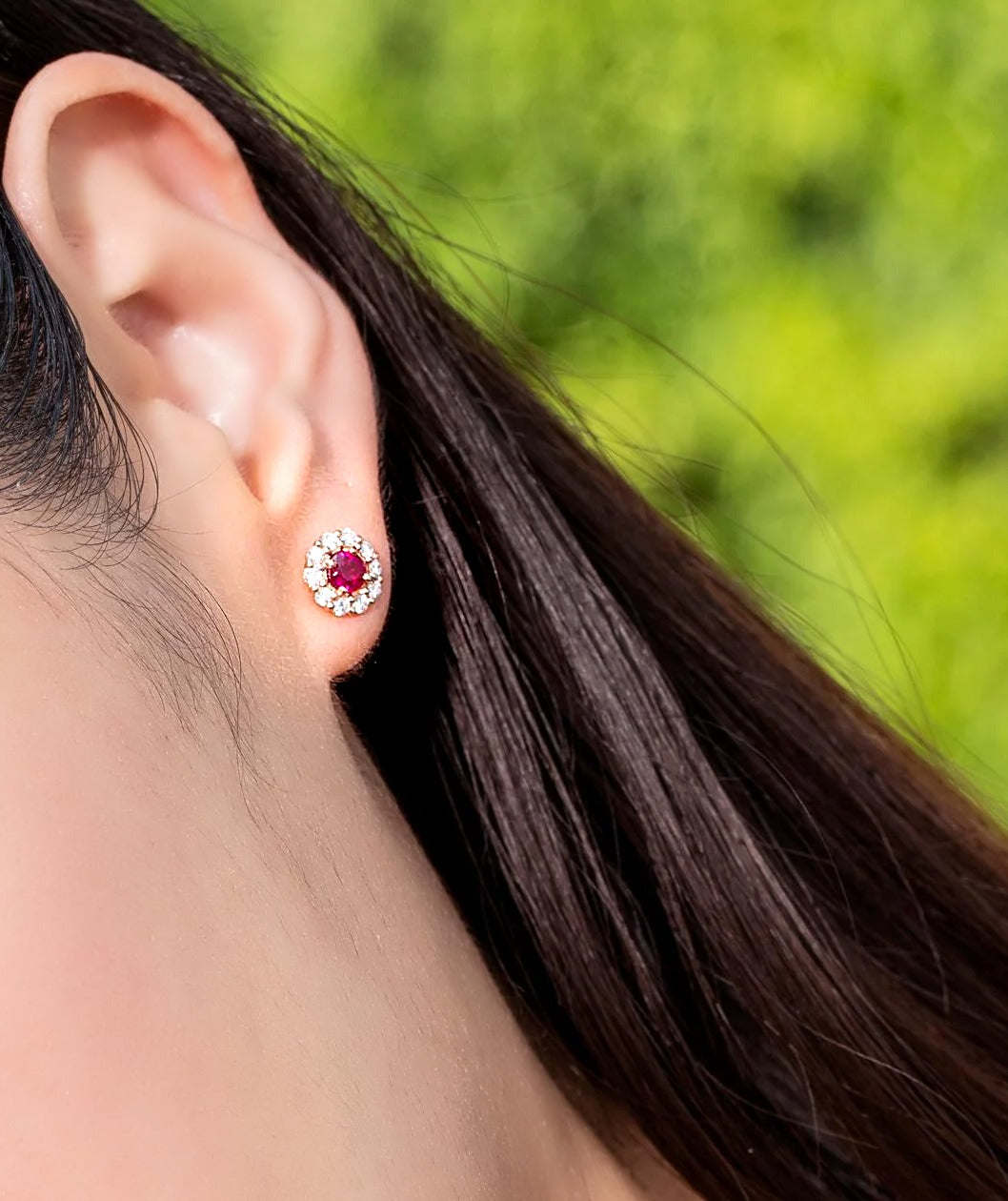 Ruby and diamond halo stud earring in 18K gold, worn on the ear