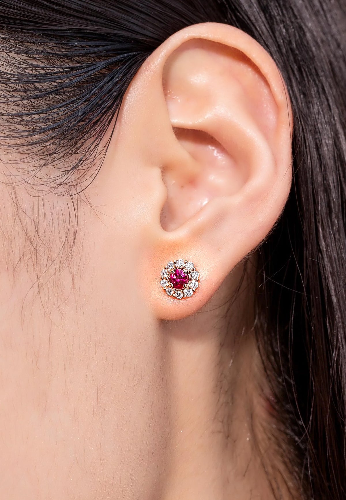 Ruby and diamond halo stud earring in 18K gold, worn on the ear