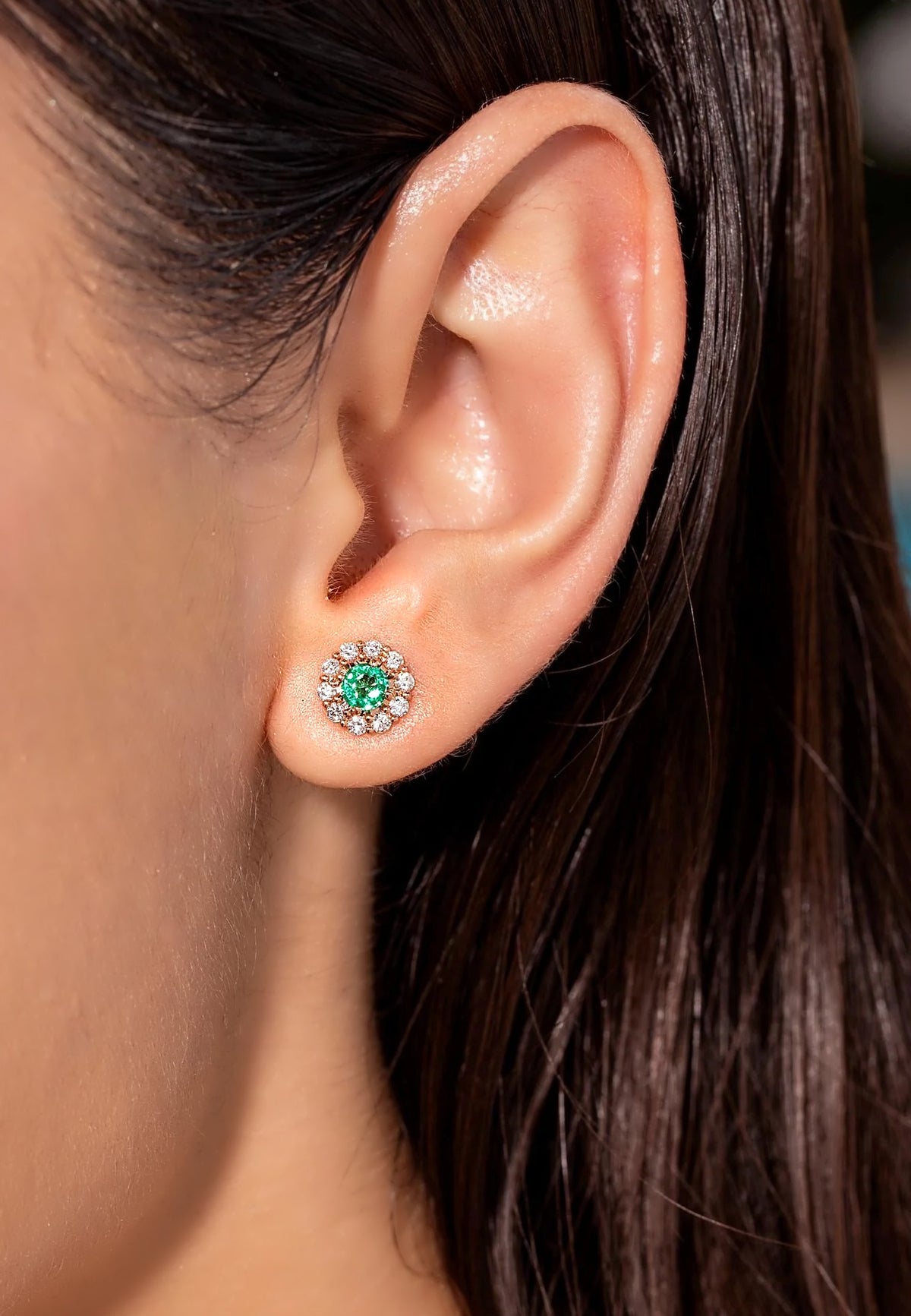 Ohrstecker mit sambischem Smaragd und Diamant-Blüten-Halo in 18K Gelbgold, am Ohr getragen