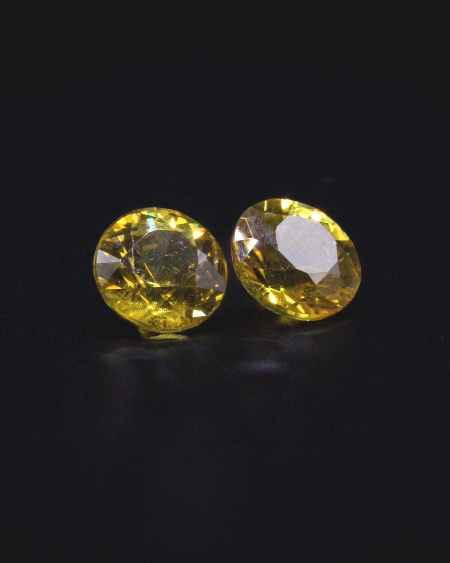 0.70 ct pair of natural yellow sapphires from Thailand, 4 mm rounds, face-up on dark grey