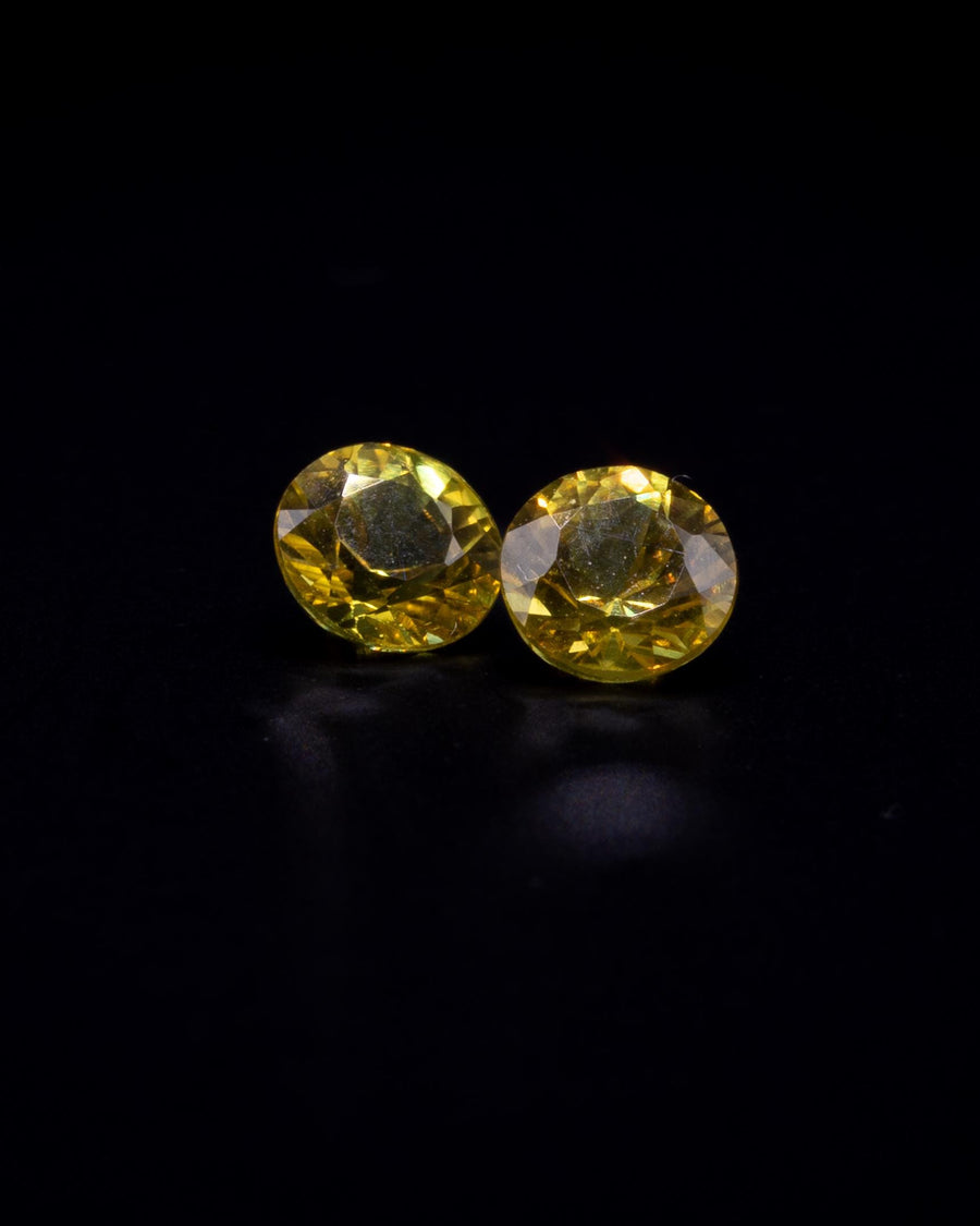 Matched pair of natural yellow sapphires, 0.68 ct total, 4 mm round brilliants, on black