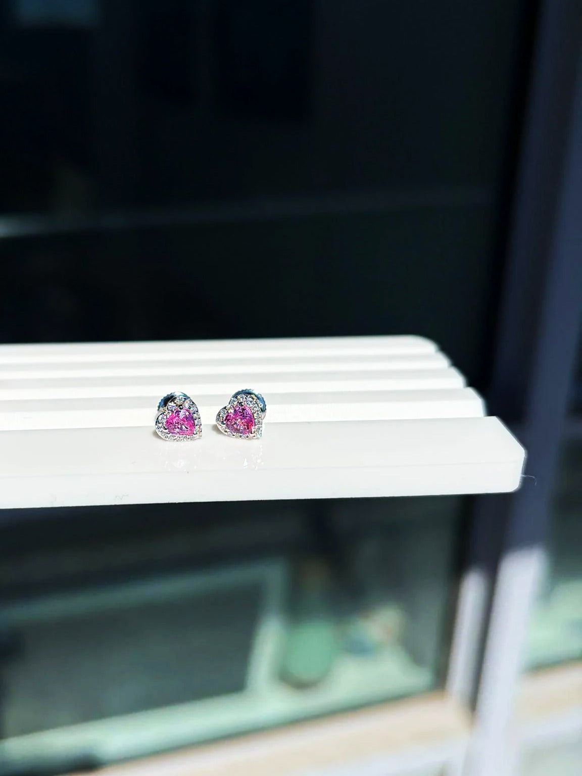 Pendientes de botón pequeños de corazón con zafiro rosa y diamantes en oro blanco de 18K sobre un expositor blanco