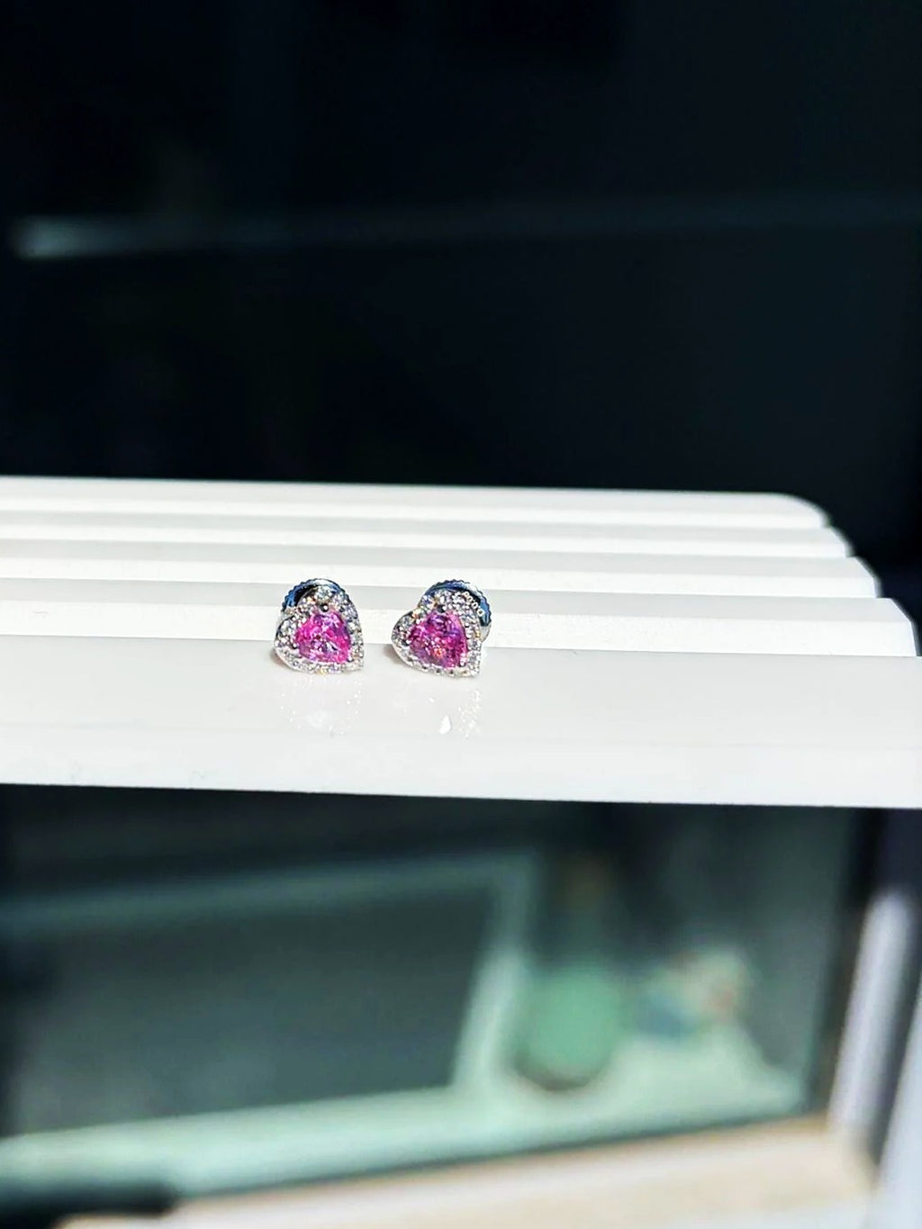 Pendientes de botón pequeños de corazón con zafiro rosa y diamantes en oro blanco de 18K sobre un expositor blanco