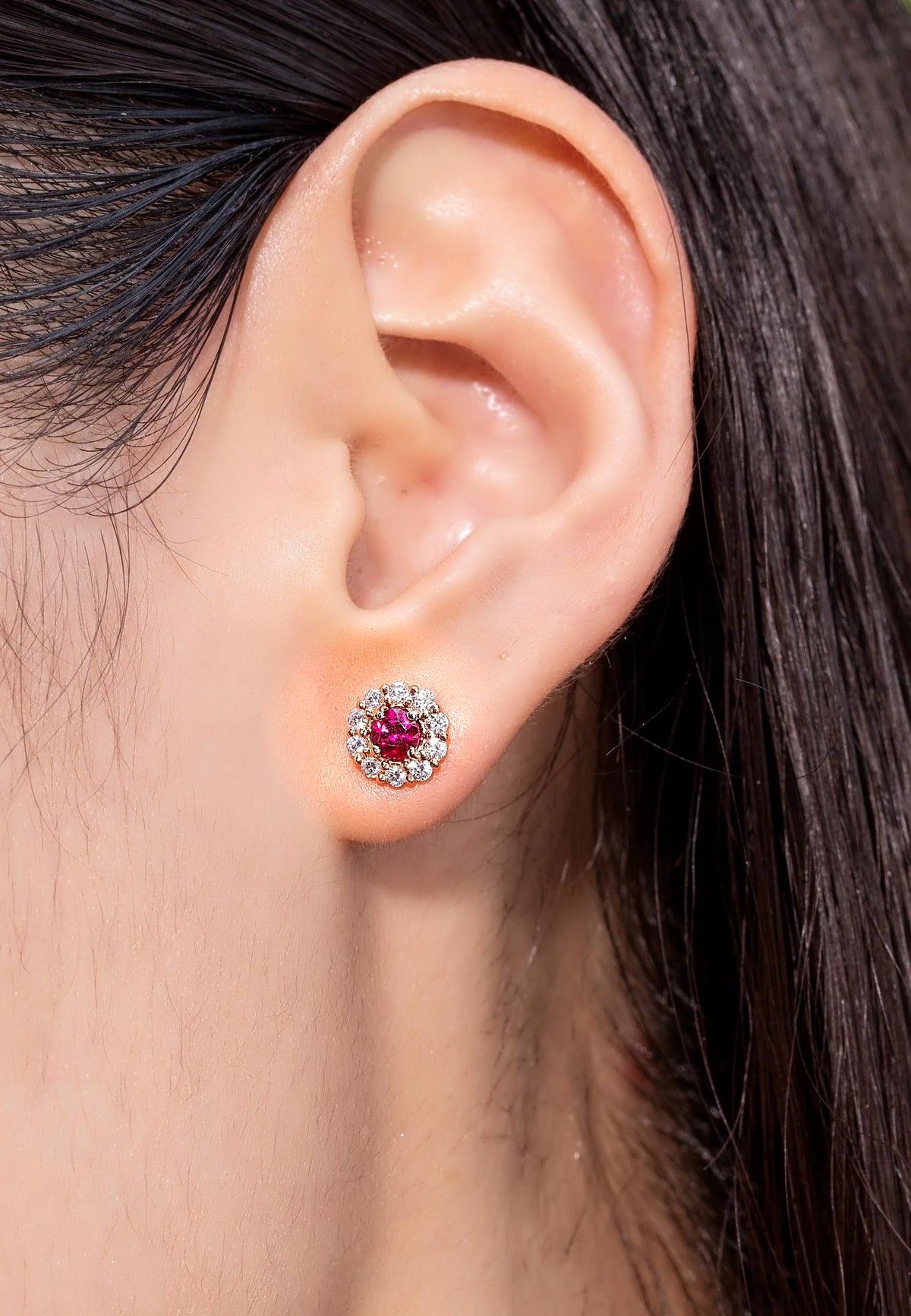 Ruby and diamond halo stud earring in 18K gold, worn on the ear