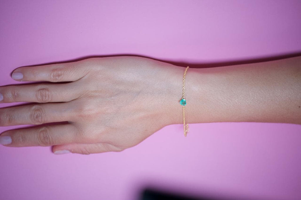 Minimalist emerald heart bracelet worn on the wrist, everyday gold plated sterling silver
