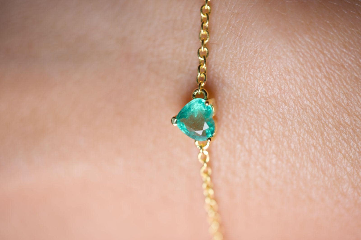 Close-up of the prong-set emerald heart on a dainty yellow gold plated sterling silver chain