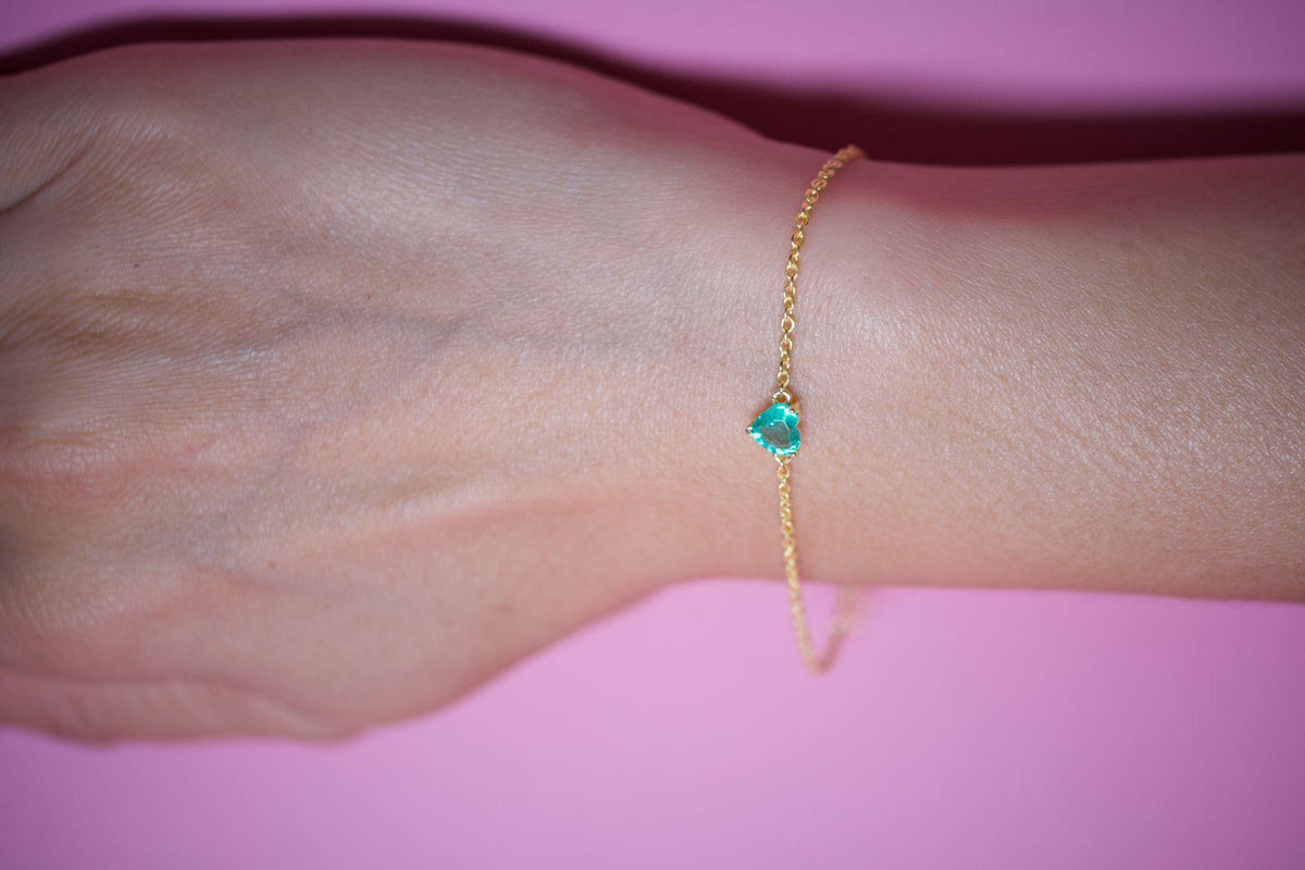 Faceted heart-cut emerald bracelet on the wrist with a dainty gold plated 925 silver chain