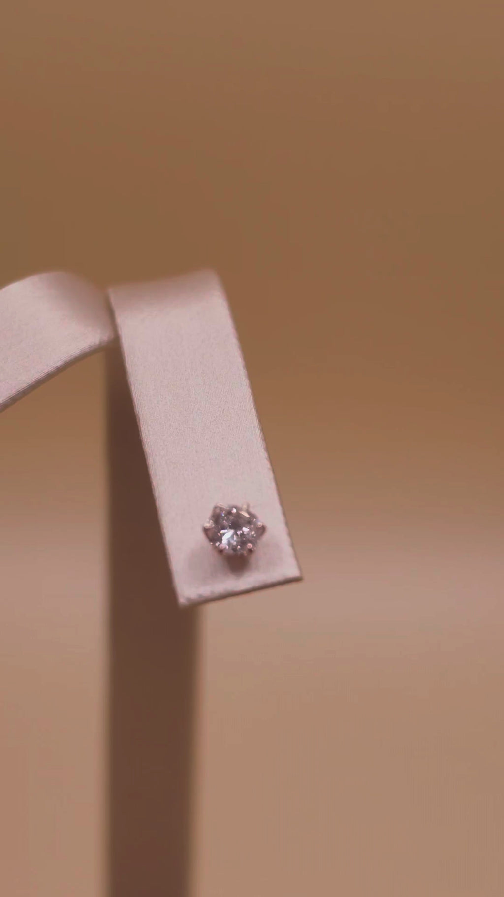 Video: pair of 0.50 ct diamond studs on a T-bar stand, sparkle in warm light