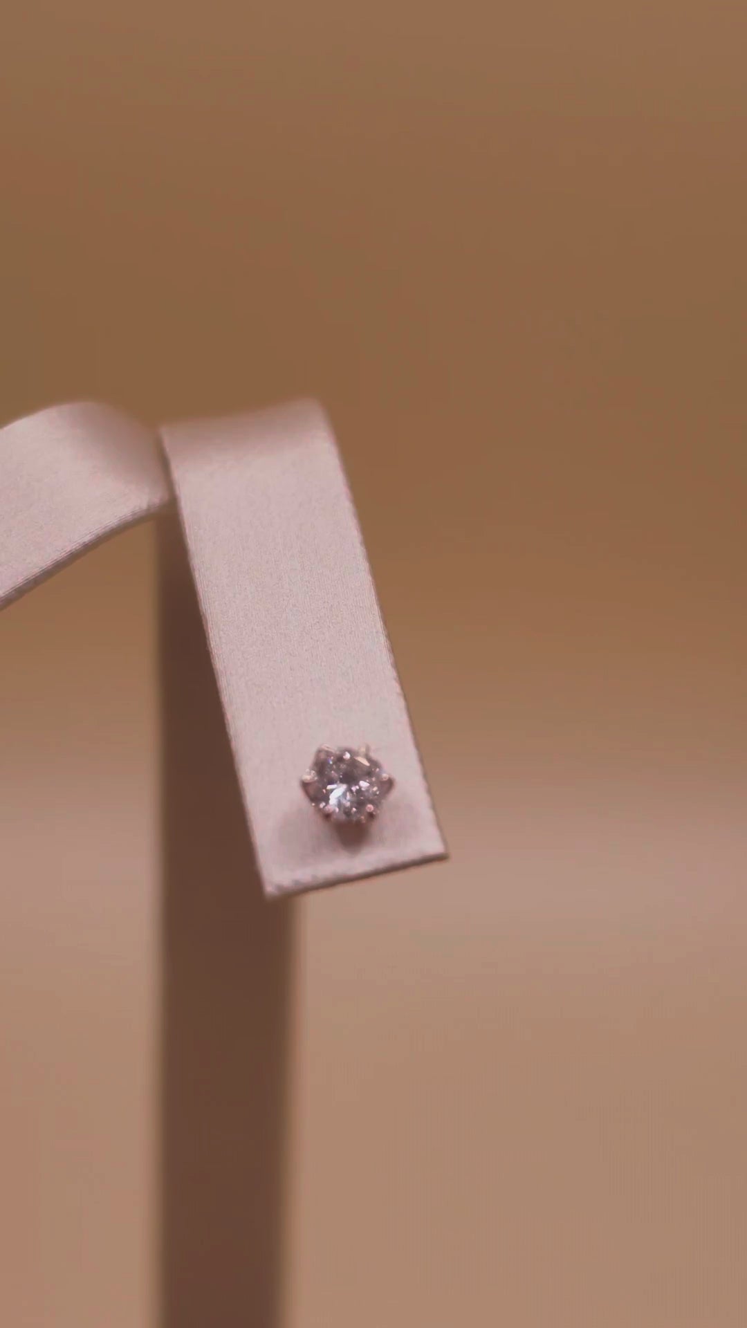 Video: pair of 0.50 ct diamond studs on a T-bar stand, sparkle in warm light