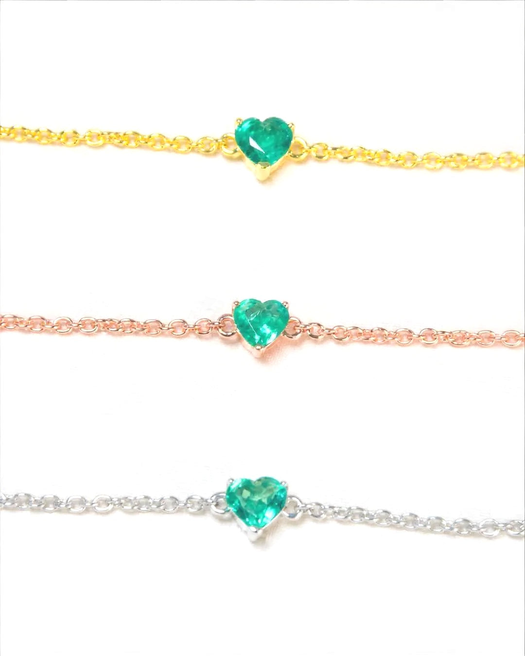 Natural emerald heart bracelets in yellow gold, rose gold and white rhodium plated 925 sterling silver, each with a 5mm heart-cut Zambian emerald