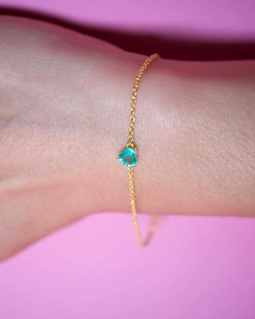 Faceted heart-cut emerald bracelet on the wrist with a dainty gold plated 925 silver chain